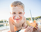 Caucasian boy eating cantaloupe slice, American Fork, Utah, USA
