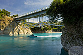 Speedboat driving beneath the bridge over the Rakaia Gorge, Canterbury, South Island, New Zealand