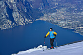 Frau auf Skitour steigt zum Monte Baldo auf, Gardasee im Hintergrund, Monte Baldo, Gardaseeberge, Trentino, Italien