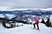 Female back-country skier ascending to Sonntagshorn, Berchtesgaden Alps in background, Chiemgau Alps, Salzburg, Austria