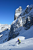 Female back-country skier downhill skiing from Cristallo wind gap, Cristallo, Dolomites, Belluno, Veneto, Italy