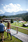 Paar spaziert Hand in Hand, Badehaus im Hintergrund, Hotel Das Kranzbach, Klais, Krün, Oberbayern, Bayern, Deutschland