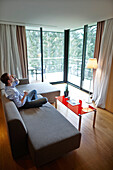Mann sitzt auf einer Couch einer Suite, Hotel K, Baerenthal, Moselle, Lothringen, Frankreich