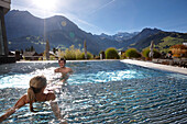 Couple in a hotel outdoor pool, Engstligenalp and Wildstrubel in background, Adelboden, Canton of Bern, Switzerland