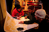 Drei Männer betrachten eine Seekarte im Segelboot Tari II, Magellanstraße, Chile