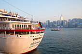 Cruise ship MS Deutschland, Reederei Peter Deilmann, at Ocean Terminal with Star Ferry in Hong Kong harbor and skyline in distance, Tsim Sha Tsui, Kowloon, Hong Kong