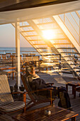 Woman relaxing in a deck chair aboard cruise ship MS Deutschland, Reederei Peter Deilmann, South China Sea, near Taiwan