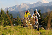 Mountain bikers passing Winklmoosalm, Lofer Mountains in background, Chiemgau, Upper Bavaria, Germany