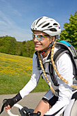 Young woman riding a racing bicycle, Upper Bavaria, Germany