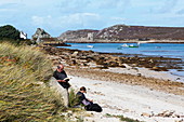 Paar ruhen sich aus am Strand, Anneka's Quay, Bryher, Isles of Scilly, Cornwall, England, Grossbritannien