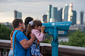 Vater hält Tochter hoch um durch ein Münzfernglas am Aussichtspunkt Sperlingsberge auf die Stadt zu schauen, Moskau, Russland