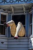 Two inflatable women's legs stick wearing black mesh stockings protrude from a window in fabled 1960's counter culture location in the Haight-Ashbury section of San Francisco.
