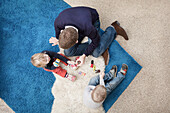 Father playing with son and daughter on sofa with toy cars