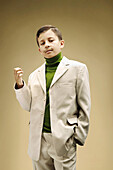 Young boy dressed in beige suit with fake mustache