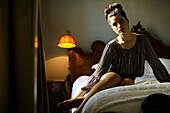 Woman sitting on bed in hotel room