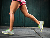 Legs of woman running on street