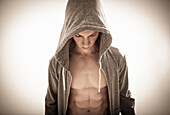 Man in hoodie with muscular body looking down