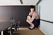 Businesswoman crouching in small conference room