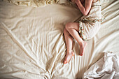Lower section of girl lying on bed