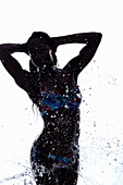Young woman being splashed with water, silhouette