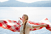 Young woman holding blanket by lake, Hadley, New York, USA