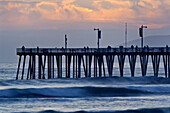 Sunset light over the pier and ocean waves at Pismo Beach, San Luis Obispo County coast, California.