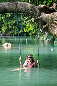 Woman on a swing in the Blue Lagoon in Vang Vieng, Laos.