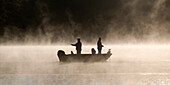 Two Men Fishing Off Their Boat On A Misty Morning, Ontario
