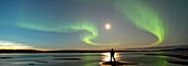 Person Standing Under The Aurora Borealis While The Mackenzie River Flows By, Fort Simpson, Nwt.