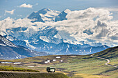 Tour Bus Travels On The Park Road With The North Summit Of Mt. Mckinley Visible And Towering Over The Landscape, Denali National Park, Alaska