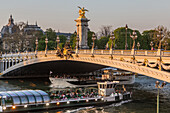 Cruise on the seine and ferries below the pont alexandre iii bridge at the end of the day, 7th arrondissement, paris, france