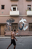 Soccer players on the street in front of a building covered in graffiti, havana, cuba, the caribbean