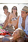 Two Young Couples Sitting and Sunbathing on Edge of Pier