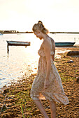 Junge blonde Frau geht am Ufer entlang