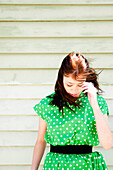 Junge Frau in grünem Kleid mit Polka Dots blickt nach unten