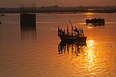 Silhouette of a man driving his boat on the Yamuna river at sunset in Vrindavan, India