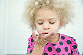 Mixed race girl blowing sparkles from hand, Seattle, Washington, USA