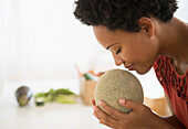 Black woman smelling cantaloupe, Jersey City, New Jersey, USA