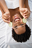Portrait of smiling Black woman holding cucumber slices, Jersey City, New Jersey, USA