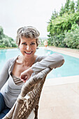 Woman smiling in armchair by swimming pool, Palma de Mallorca, Balearic Islands, Spain