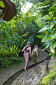 Mother and children walking along stone path, Ubud, Bali, Indonesia