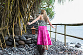 Caucasian girl walking along stone ledge, Candidasa, Bali, Indonesia