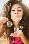 Mixed race woman blowing bubbles, Jersey CIty, New Jersey, USA