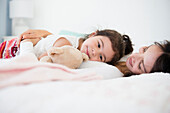 Hispanic mother and daughter relaxing on bed, Jersey City, New Jersey, USA