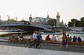 France, Paris, strollers on the south bank of the Seine, Pont Alexandre III and Grand Palais.
