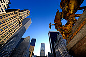 diving against an equestrian statue and a golden angel, surrounded by building in Manhattan