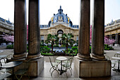 the garden of the Petit Palais in Paris and building. Two columns frame table and chairs