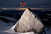Snowboarder jumpling on a rock for the sunset