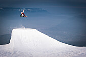 France, Grenoble, snowboarder jumping with grenoble city in the back