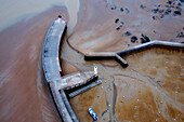 aerial view of a harbor at low tide. A vessel aground. Dikes on the left and right